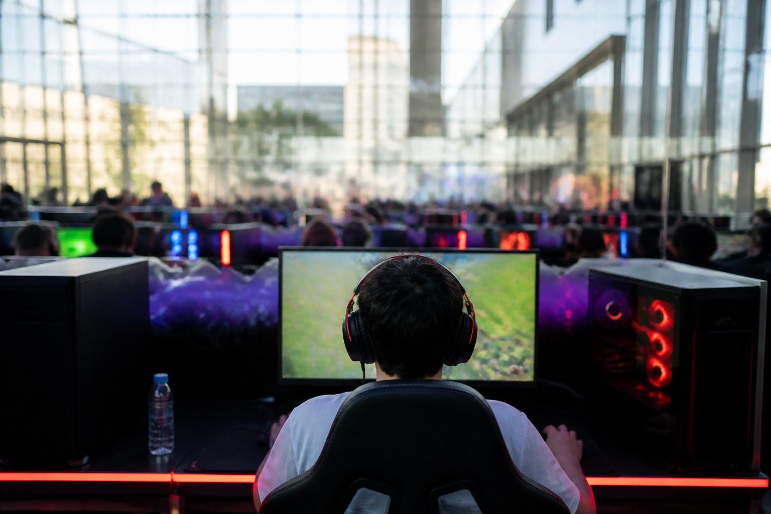 Player in headphones focused at a lit gaming station, seen in side profile